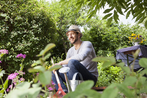 Lächelnder Mann auf Gartenterrasse sitzend - RBF003157