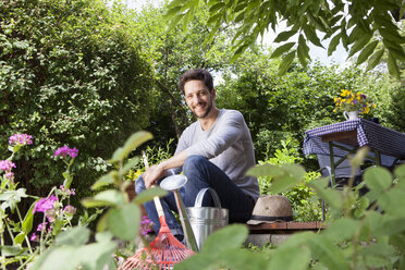 Lächelnder Mann auf Gartenterrasse sitzend - RBF003158