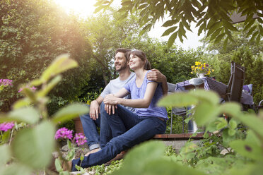 Smiling couple sitting on garden terrace - RBF003162