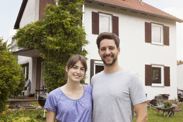 Portrait of smiling couple in garden in front of residential house - RBF003166
