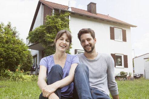 Porträt eines lächelnden Paares im Garten vor einem Wohnhaus - RBF003169