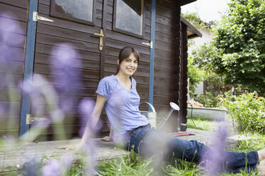 Lächelnde Frau am Gartenhäuschen sitzend - RBF003206