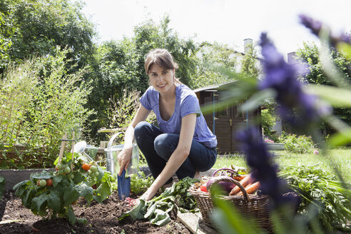 Lächelnde Frau bei der Gartenarbeit im Gemüsebeet - RBF003177
