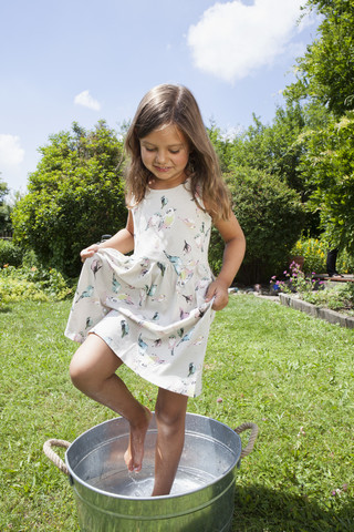 Mädchen nimmt ein Fußbad im Zinkeimer, lizenzfreies Stockfoto
