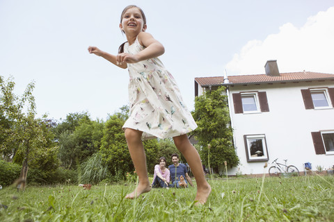 Verspieltes Mädchen mit Eltern im Garten, lizenzfreies Stockfoto