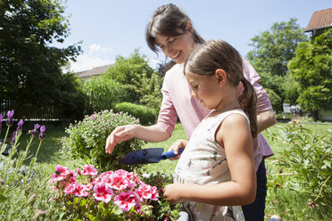 Lächelnde Mutter und Tochter im Garten, die Blumen pflanzen - RBF003226