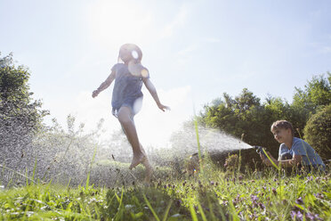 Boy and girl splashing with water in garden - RBF003255