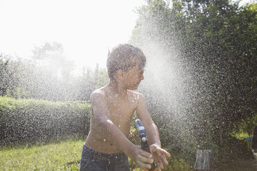 Junge spritzt mit Wasser im Garten - RBF003263