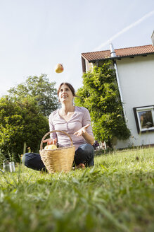 Lächelnde Frau, die im Garten sitzt und einen Apfel erbricht - RBF003196