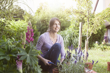 Smiling woman gardening in flowerbed - RBF003198