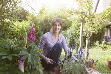 Smiling woman gardening in flowerbed - RBF003199