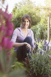 Smiling woman gardening in flowerbed - RBF003200