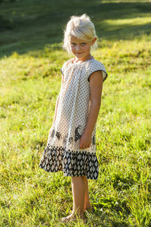 Porträt eines lächelnden blonden kleinen Mädchens im Sommerkleid auf einer Wiese - TCF004902