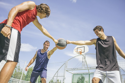 Drei junge Männer spielen Basketball, lizenzfreies Stockfoto