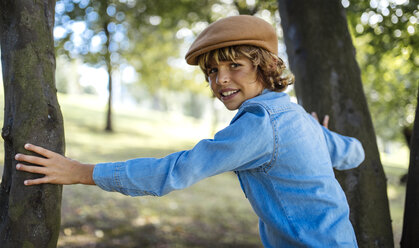 Portrait of blond boy wearing cap standing between two trees - MGOF000757