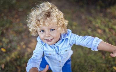 Porträt eines lächelnden blonden kleinen Jungen, der zur Kamera aufschaut - MGOF000765