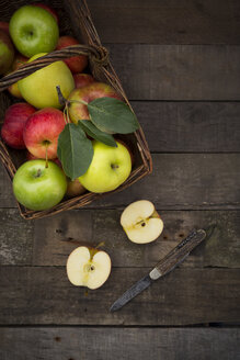 Verschiedene Äpfel, Korb und Taschenmesser auf Holz - LVF003842