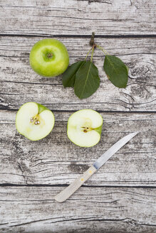 Geschnittener und ganzer Granny Smith, Blätter und Küchenmesser auf Holz - LVF003860