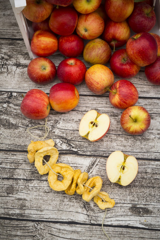 Ganze und geschnittene rote Äpfel und Apfelchips auf Holz, lizenzfreies Stockfoto