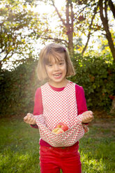 Porträt eines kleinen Mädchens, das mit seinem Kleid Äpfel hält - LVF003873