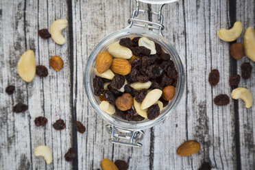 Mixed nuts and raisins in glass on wood - LVF003879