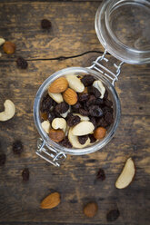 Mixed nuts and raisins in glass on wood - LVF003880