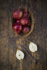 Wickerbasket of organic red Clapp's Favourite and a sliced one on dark wood - LVF003899