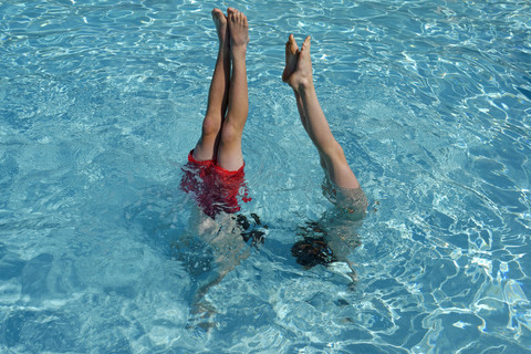 Teenager und Mädchen machen einen Handstand im Schwimmbad, lizenzfreies Stockfoto