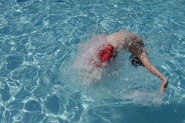 Teenage boy jumping and playing in swimming pool stock photo