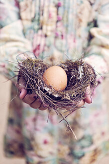 Mädchen hält ein Ei in einem Nest - XCF000027