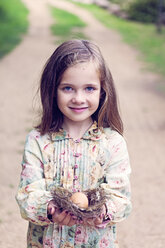 Lächelndes Mädchen hält ein Ei in einem Nest - XCF000028