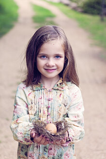 Smiling girl holding an egg in a nest - XCF000028