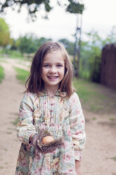 Lächelndes Mädchen hält ein Ei in einem Nest - XCF000029