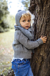 Porträt eines kleinen Jungen in Herbstmode neben einem Baumstamm - MGOF000781