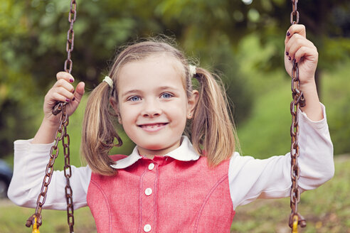 Porträt eines lächelnden kleinen Mädchens mit Zöpfen auf einer Schaukel - XCF000034