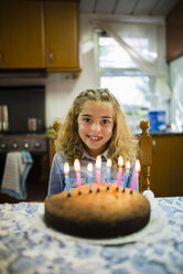 Porträt eines glücklichen kleinen Mädchens mit Geburtstagstorte zu Hause - RAEF000508
