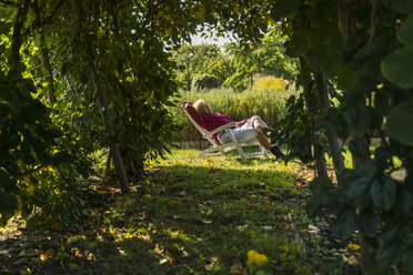 Senior woman relaxing in garden chair - UUF005739