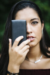 Junge Frau bedeckt ein Auge mit Smartphone - JRFF000079