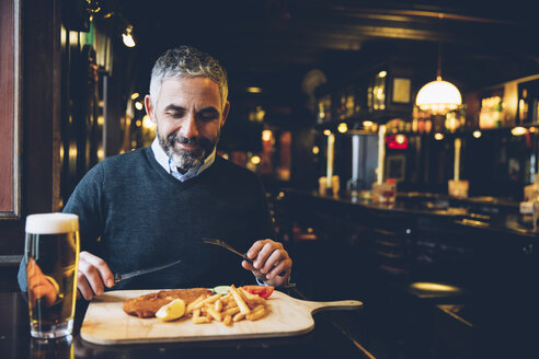 Lächelnder Mann in einem Restaurant mit Wiener Schnitzel und Pommes frites - AIF000094