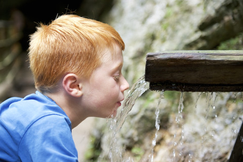 Boy drinking water from a runlet stock photo