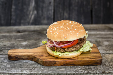 Hausgemachter Burger mit Salat, Fleisch, Tomate und Zwiebel auf Schneidebrett - SARF002133