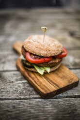 Homemade veggie burger with aubergine, lettuce, tomato and onion on chopping board - SARF002135