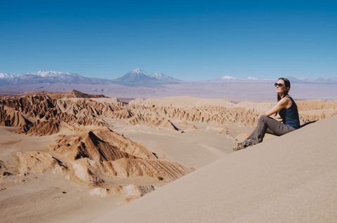 Chile, Atacama-Wüste, Frau sitzt auf einer Düne und betrachtet die Aussicht, lizenzfreies Stockfoto