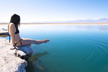 Chile, Atacama Desert, woman in bikini dipping her feet in Laguna Cejar - GEMF000402