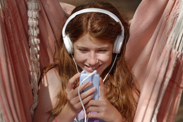 Portrait of girl with headphones and smartphone in a hammock - LBF001216