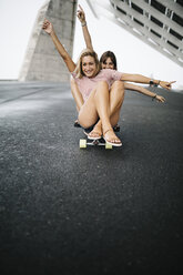 Zwei junge Frauen fahren auf einem Longboard - JRFF000091