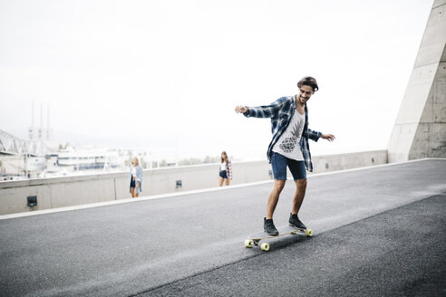 Junger Mann balanciert auf Longboard, Mädchen schauen zu - JRFF000097