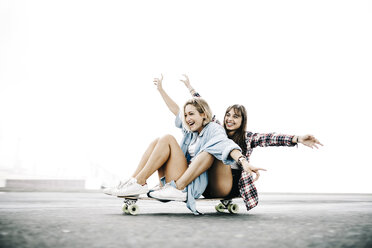 Two young women cruising on a longboard - JRFF000098