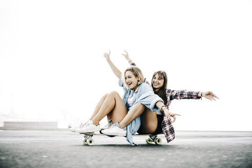 Zwei junge Frauen fahren auf einem Longboard - JRFF000098