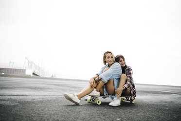 Two young women sitting on a longboard - JRFF000099